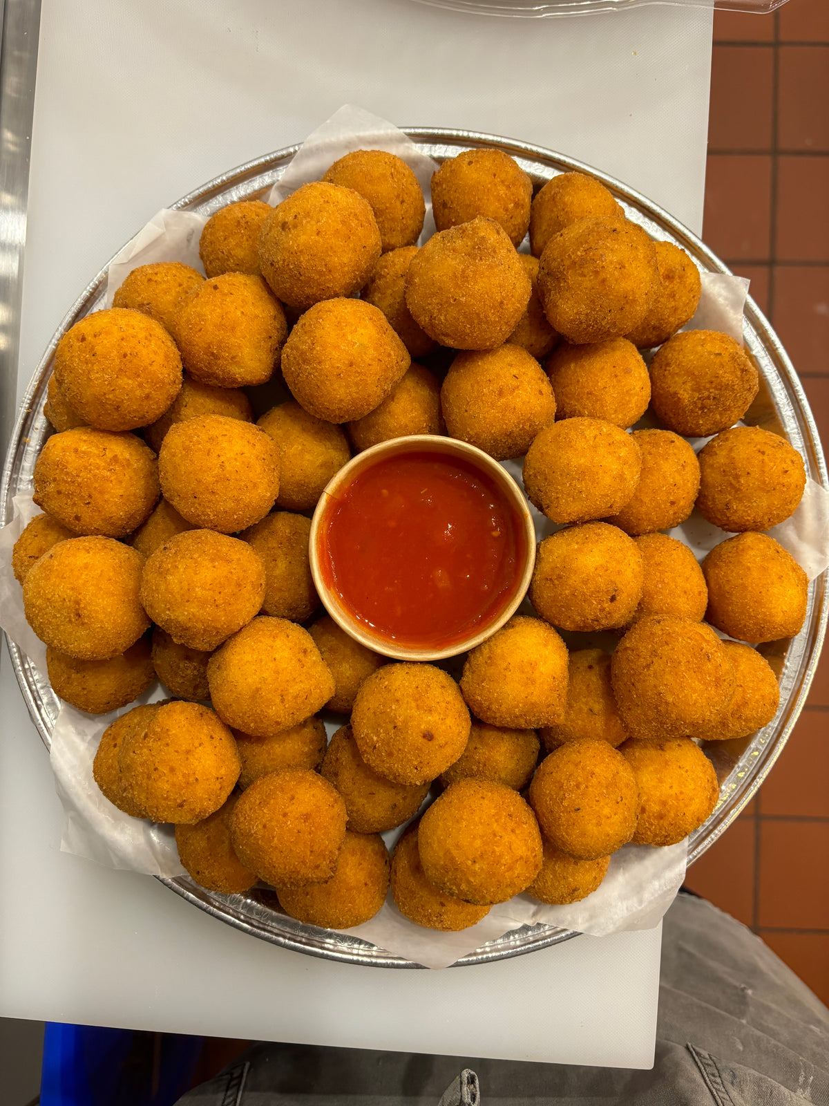 Freshly fried mini arancini arranged around marinara sauce